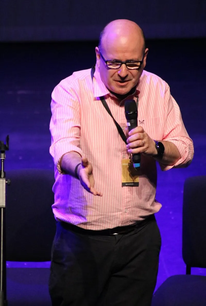 Ian Mayer speaking on stage, mic in hand
